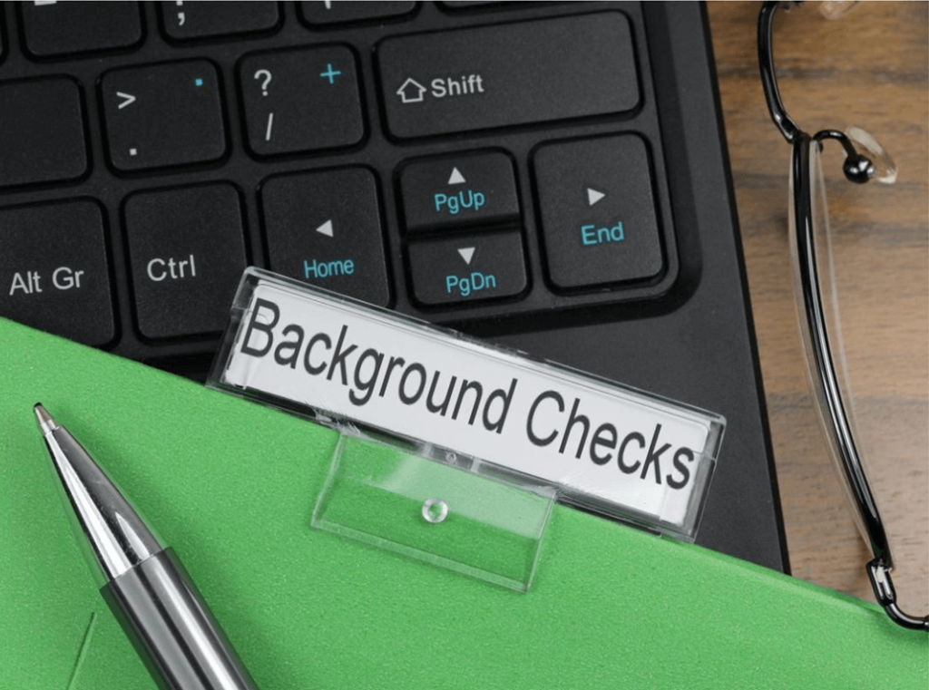 Close-up of background checks folder on desk with laptop and pen
