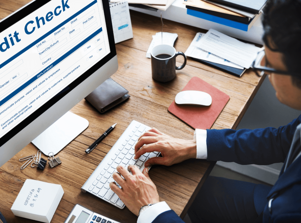 Top-down view of a professional performing a digital credit check on a computer screen as part of a background screening process.