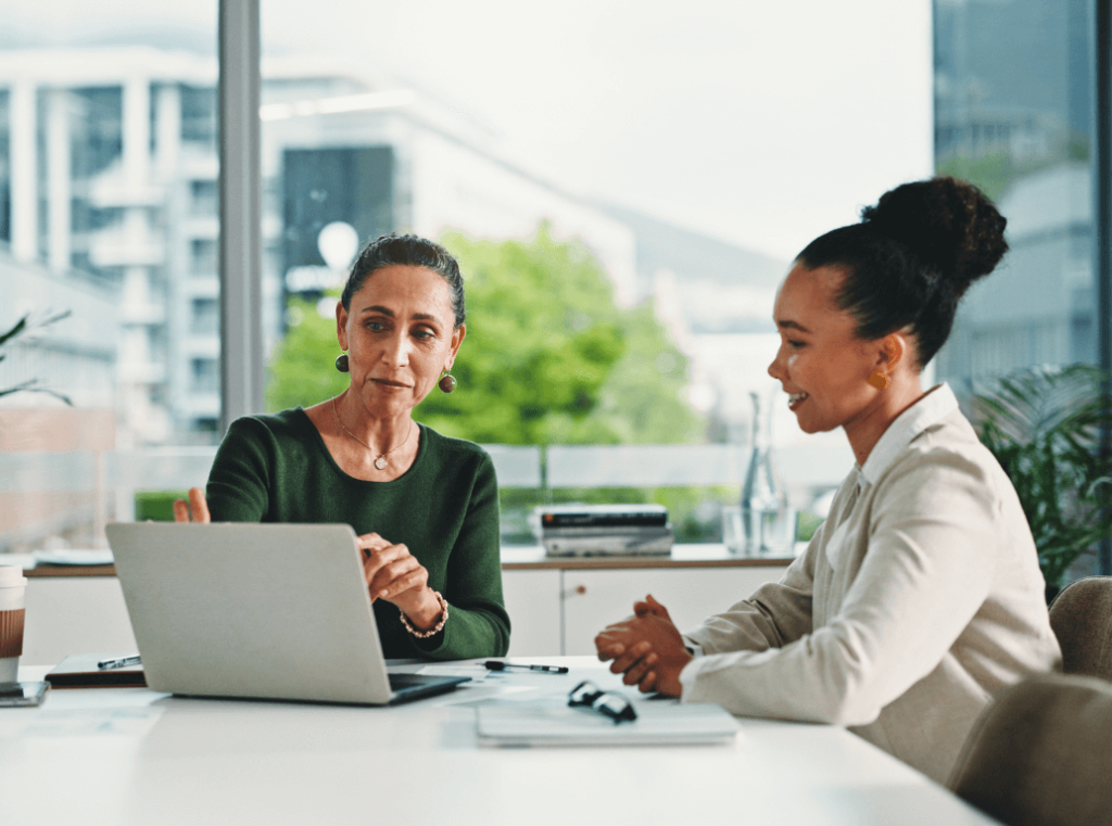 Two HR professionals collaborating and reviewing a strategic hiring calendar on a laptop.
