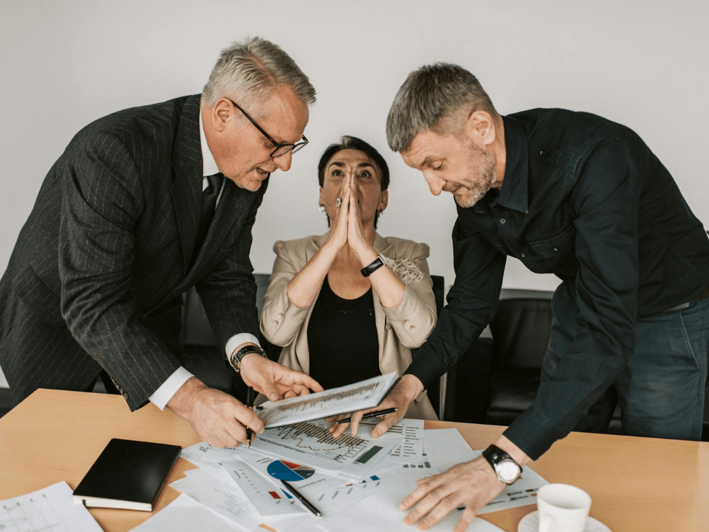 Stressed coworkers looking at company records, highlighting the stakes of finance hiring.